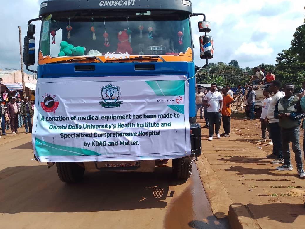 Close-up of KDAG and MATTER donation banner on truck announcing medical equipment donation to Dambi Dollo University Health Institute and Specialized Comprehensive Hospital